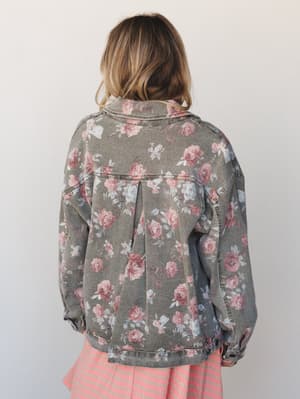Shot from the back, a floral-printed denim jacket in faded khaki layers over a pink striped skirt — the kind of piece that looks like it's been loved for years and somehow only gets better.