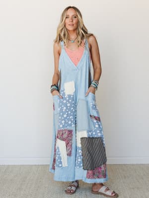 A wide-leg patchwork denim jumpsuit layered over a coral tank, styled with beaded bracelets, a turquoise necklace, and sandals — the kind of outfit that looks like it was assembled with intention and a great thrift store.