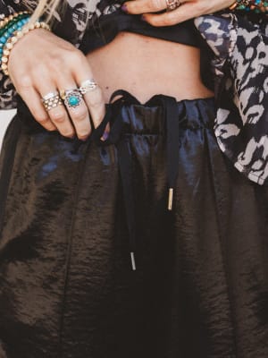 Person wearing a black outfit with jewelry, including rings and bracelets.