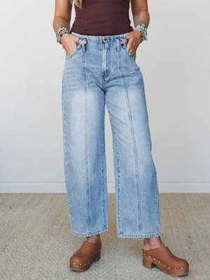 Light wash wide-leg jeans with front seam detailing and an elastic waistband, styled with a dark burgundy tank, stacked turquoise bracelets, and wood-studded clogs — casual and collected with a boho edge.