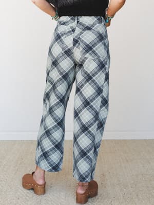 Shot from behind, these wide-leg plaid pants in soft sage and navy are styled with a black top, turquoise jewelry, and wooden clogs — the kind of outfit that looks effortless but was definitely thought about.