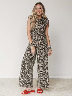 A wide-leg leopard print denim jumpsuit styled with red crochet sandals and stacked turquoise beaded bracelets — the kind of one-and-done outfit that looks like you tried without trying.