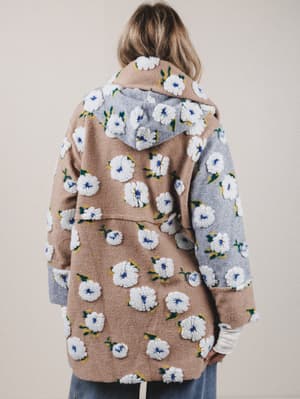 Person wearing a floral-patterned coat with a neutral background