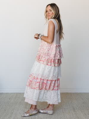 A tiered maxi skirt in white lace and mixed pink floral prints is styled with a cropped waffle-knit tank, beaded bracelets, and floral flats — soft, romantic, and effortlessly boho from every angle.