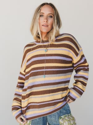 Woman wearing a striped sweater with a neutral background