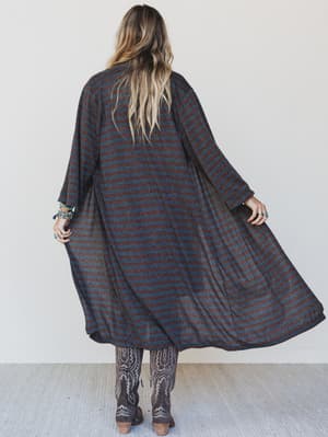 Person wearing a long, dark striped coat against a white background