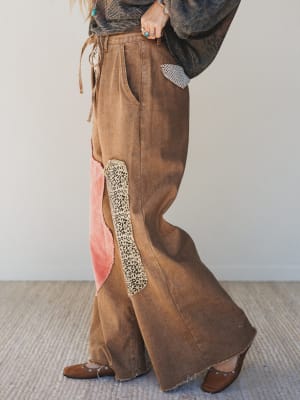 Brown wide-leg pants with a decorative panel on a neutral background