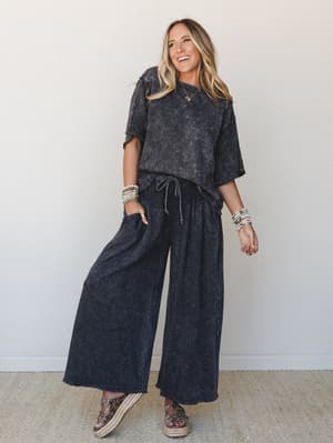 A matching acid-wash charcoal two-piece set — oversized tee and wide-leg pants with a drawstring waist — styled with stacked bead bracelets, a delicate turquoise necklace, and platform espadrille sandals for a look that's effortlessly put-together wi