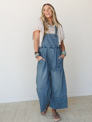 Wide-leg denim overalls styled over a blush lace top, layered with stacked beaded bracelets and a turquoise necklace — the kind of outfit that looks effortless but is absolutely a whole vibe.
