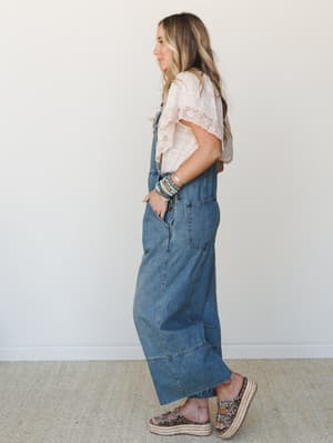 Wide-leg denim overalls styled with a blush lace-trim tee and platform sandals — the kind of effortless, put-together look that feels equally at home at a farmers market or a casual lunch with friends.