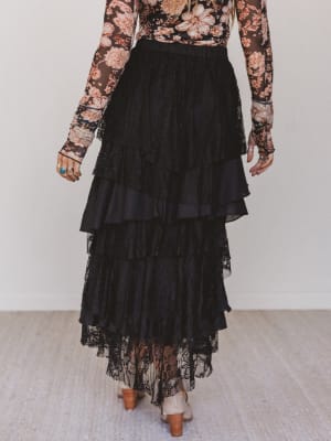 Person wearing a floral top and black lace skirt on a plain background