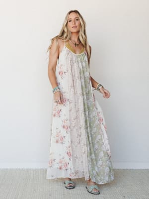 A flowy patchwork maxi dress in cream and sage floral panels worn with turquoise sandals and layered bracelets — the kind of dress that makes a Tuesday feel like something worth remembering.