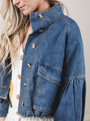 Close-up of a person wearing a blue denim jacket with a neutral background