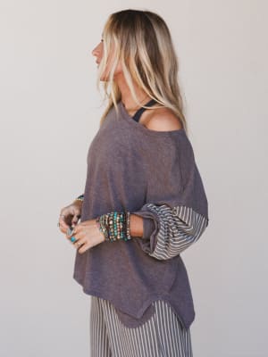 Woman wearing a purple poncho with a plain background