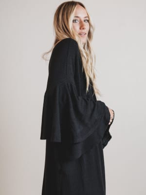 Woman wearing a black ribbed duster against a plain background