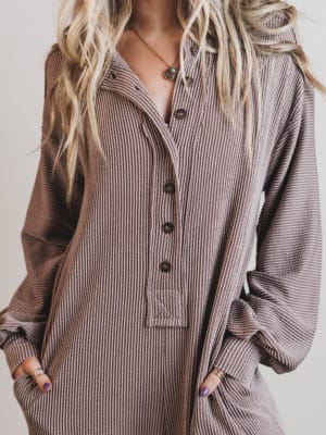 Person wearing a ribbed brown jumpsuit with a neutral background