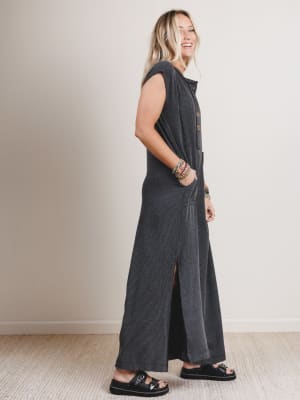Side view of woman wearing a black and gray patterned sleeveless jumpsuit with leg slits