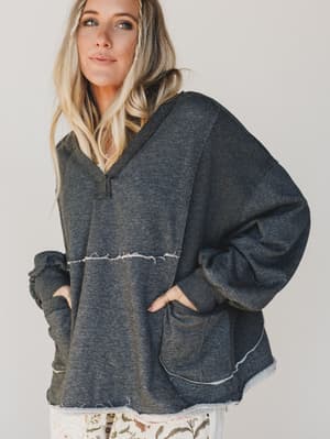 Woman wearing a dark gray hoodie with a plain background