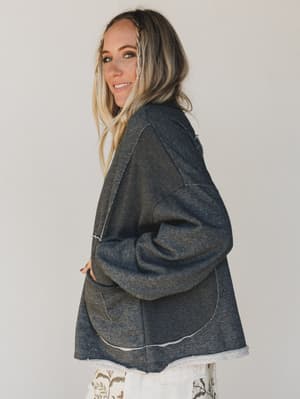 Woman wearing a dark gray hoodie against a plain background