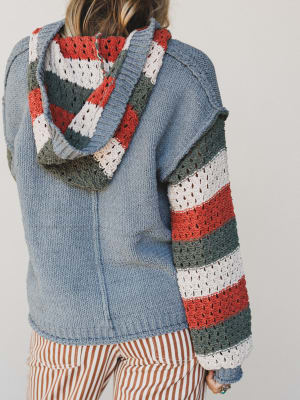 Person wearing a blue jacket with a colorful striped scarf on a plain background