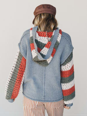 Person wearing a colorful crochet sweater with a plain background