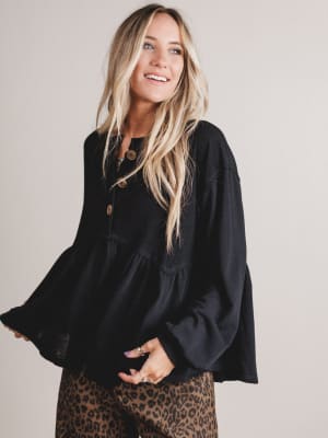 Woman wearing a black blouse with a plain background
