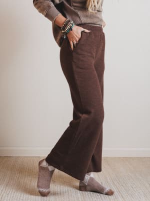 Person wearing brown corduroy pants and a sweater, standing against a plain background.