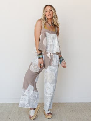 A matching patchwork two-piece set in warm mocha and white, layered with stacked beaded bracelets and a turquoise necklace — the kind of outfit that looks like it was assembled with intention but worn like a second skin.