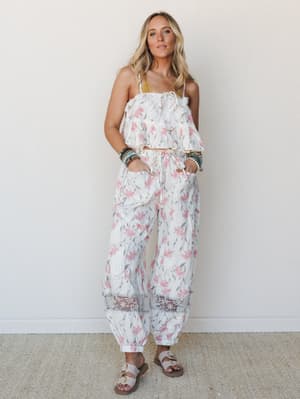 A matching floral two-piece set in ivory and pink styled with stacked beaded bracelets and slide sandals — effortlessly warm, like she packed this for a long weekend somewhere sunny.