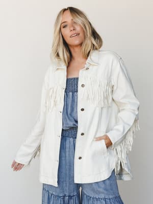 A cream fringe jacket worn open over a smocked denim dress — the kind of outfit that looks effortless but clearly had a thought behind it.