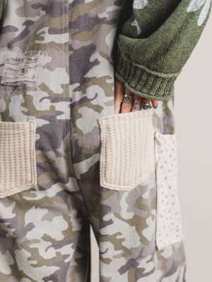 Camouflage jacket with woven pocket details on a neutral background