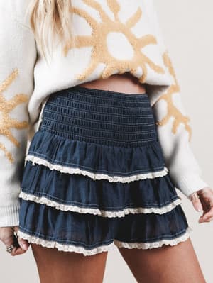 Navy denim skirt with lace trim worn by a person, against a neutral background