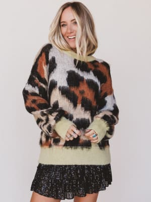 Woman wearing a patterned sweater and black skirt against a white background