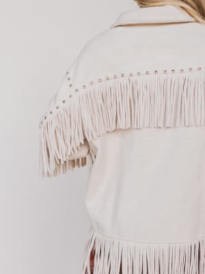 Close-up of a white fringe jacket on a plain background
