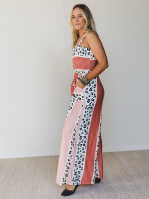 Side view of woman wearing a colorful jumpsuit with leopard print and pink accents against a plain background