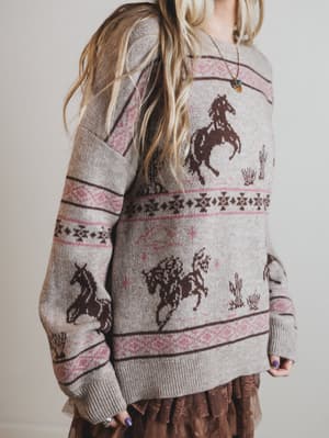Person wearing a sweater with horse patterns on a plain background