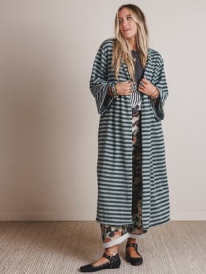 Woman wearing a long striped coat against a plain background