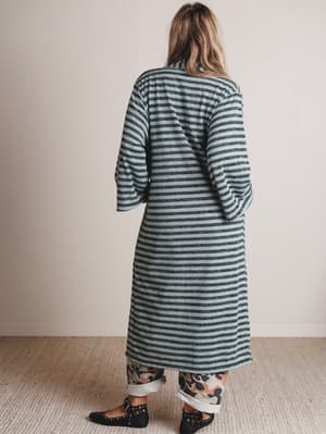 Person wearing a long, striped green and white cardigan against a plain background