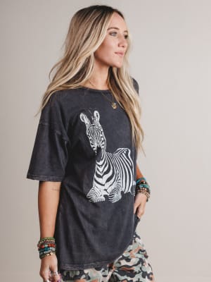 Woman wearing a black t-shirt with a zebra graphic on a plain background