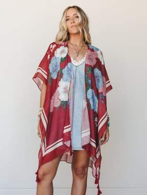 A flowy floral kimono in deep cranberry red layered over a light denim mini dress — the kind of effortless layering piece that makes a simple outfit feel intentional and a little bit magical.