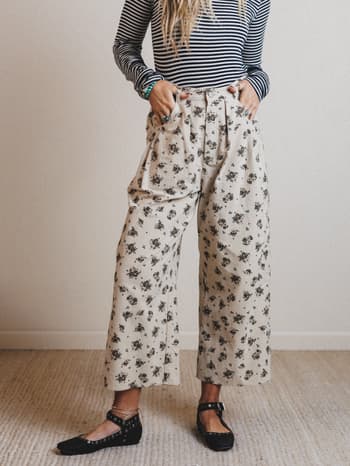 Person wearing a striped shirt and floral pants in a minimal indoor setting